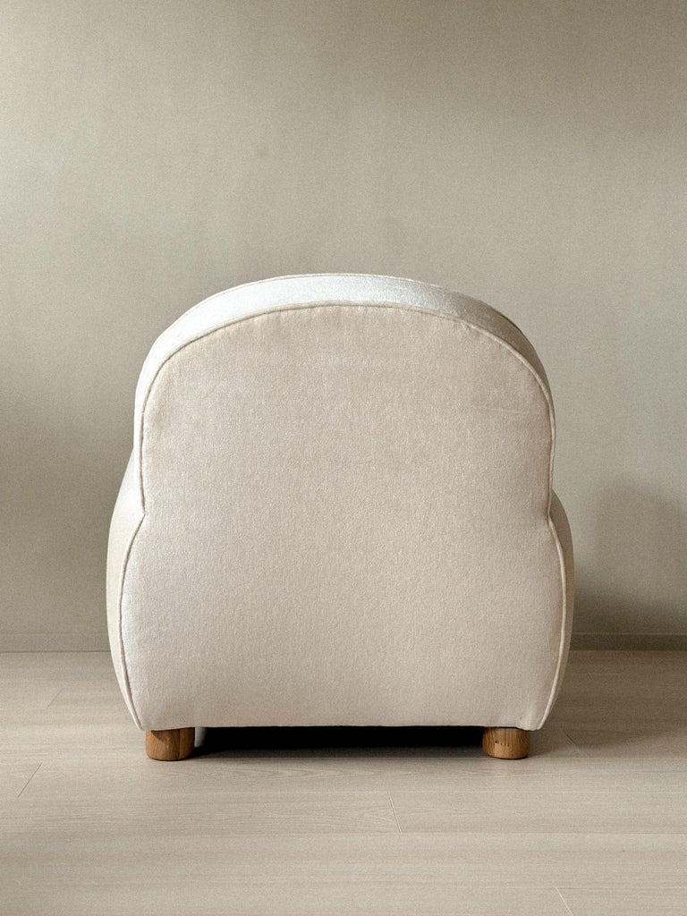 Pale velvet armchair resting on natural oak legs