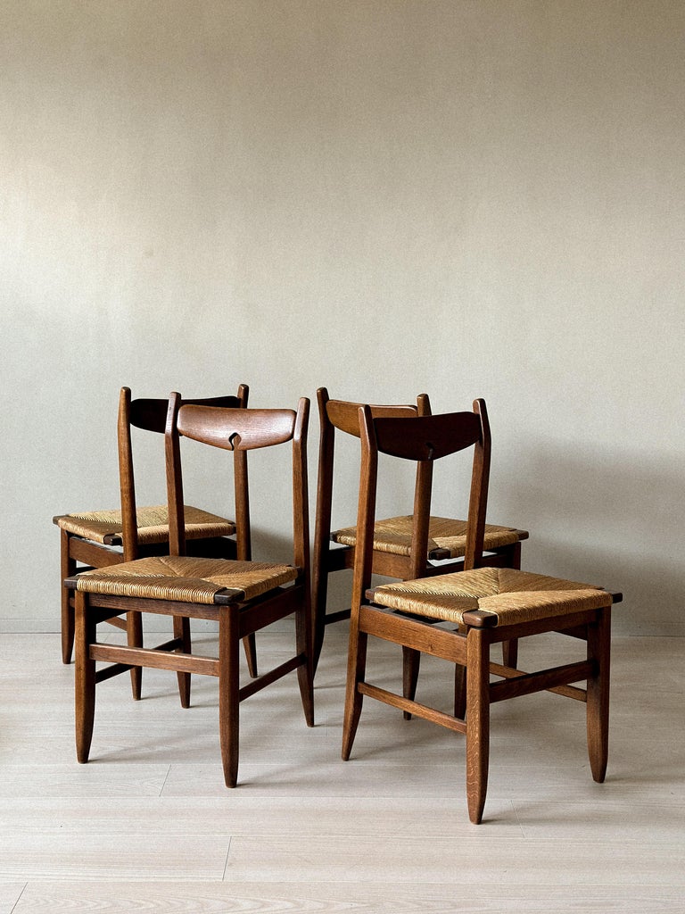 Grouped view of four oak dining chairs, France, 1960s
