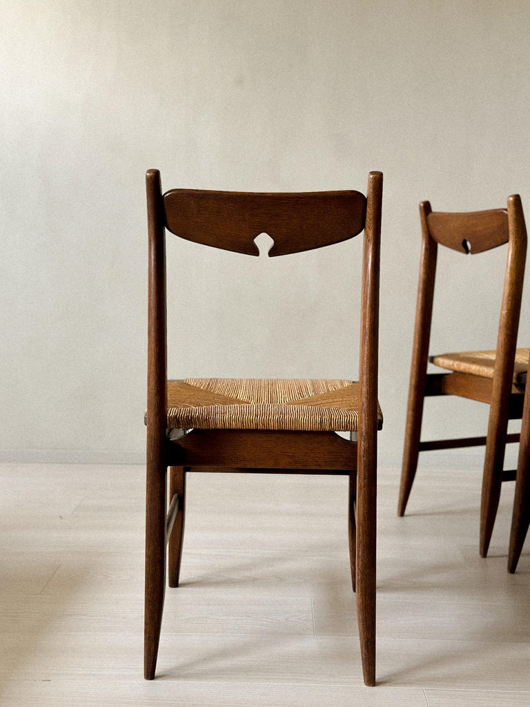 Back view of sculptural oak dining chairs with vertical slats