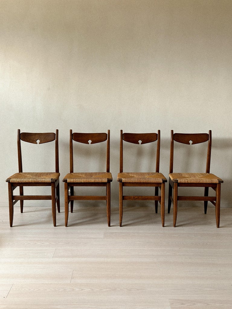 Front view of mid-century French dining chairs in oak and rush